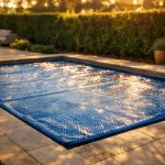 Bâche à bulles bleue posée sur une piscine rectangulaire 8 x 4 m dans un jardin résidentiel